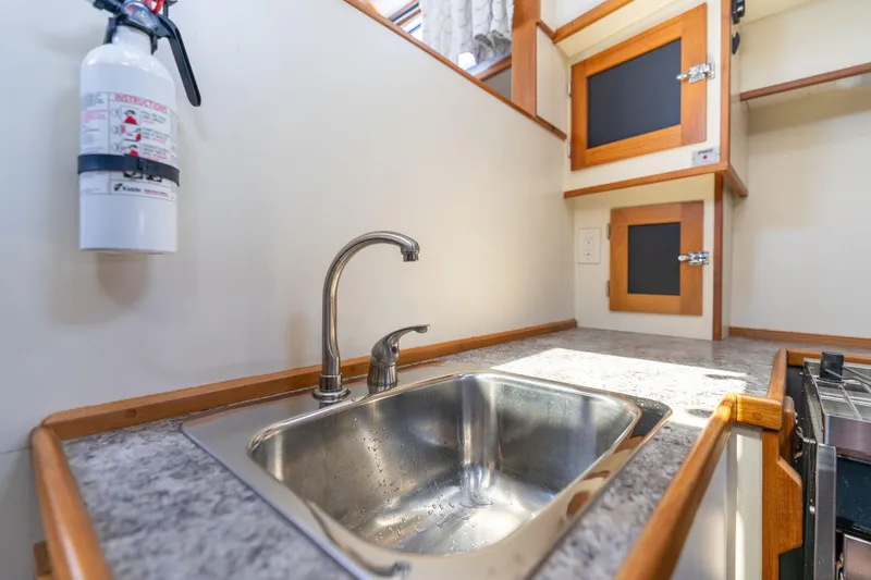 Slide: The Image of 1978 Cascade High Side kitchen with stainless steel sink, wooden cabinets, and fire extinguisher. - 20
