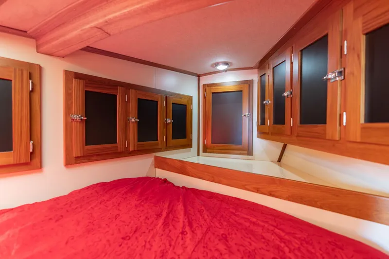 Slide: The Image of Cozy 1978 Cascade High Side interior with wooden cabinets and red bedding. - 26