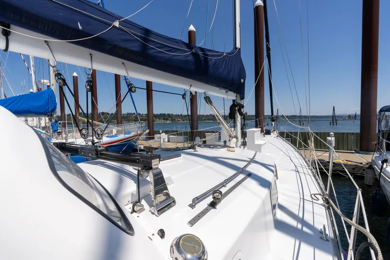 Slide: The Image of 1978 Cascade High Side sailboat docked, featuring sleek white deck and blue sail cover. - 43