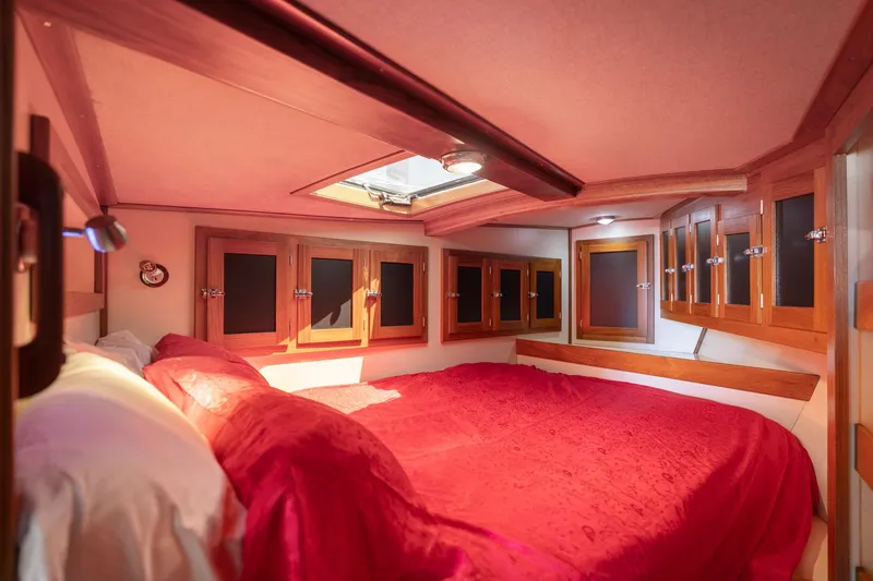 Slide: The Image of Cozy 1978 Cascade High Side boat cabin with red bedding and wooden storage cabinets. - 25