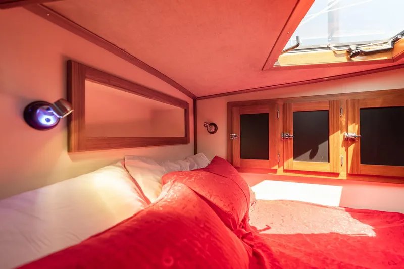 Slide: The Image of Cozy 1978 Cascade Hign Side boat cabin with red bedding and wooden accents. - 27