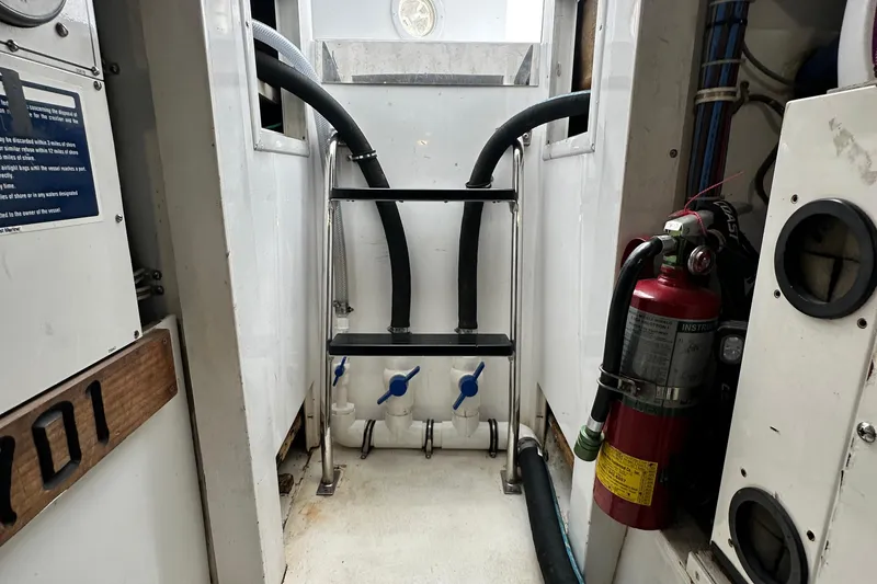 Slide: The Image of Engine room of 2002 Hatteras 50 Convertible Sportfish with fire extinguisher and plumbing. - 110