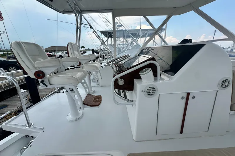 Slide: The Image of 2002 Hatteras 50 Convertible Sportfish helm with white captain chairs and control panel. - 24