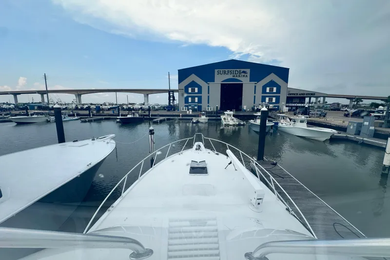 Slide: The Image of 2002 Hatteras 50 Convertible Sportfish docked at Surfside Marina, with boats and bridge in background. - 42