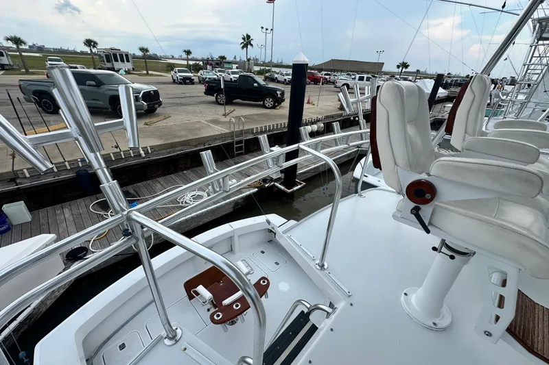 Slide: The Image of 2002 Hatteras 50 Convertible Sportfish yacht docked, featuring fishing chairs and rod holders. - 43