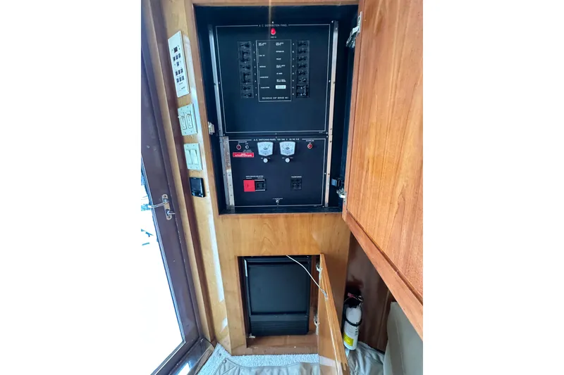 Slide: The Image of Electrical panel inside 2002 Hatteras 50 Convertible Sportfish boat, featuring control switches and fire extinguisher. - 64