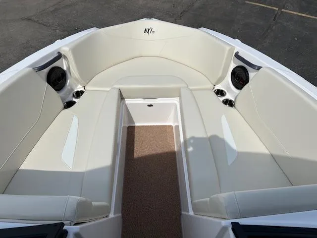 Slide: The Image of 2025 MasterCraft NXT23 boat interior with beige seating and built-in speakers. - 14