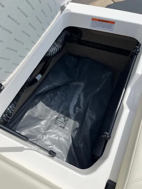 Slide: The Image of 2025 MasterCraft NXT23 storage compartment with protective cover and ventilation hose. - 20