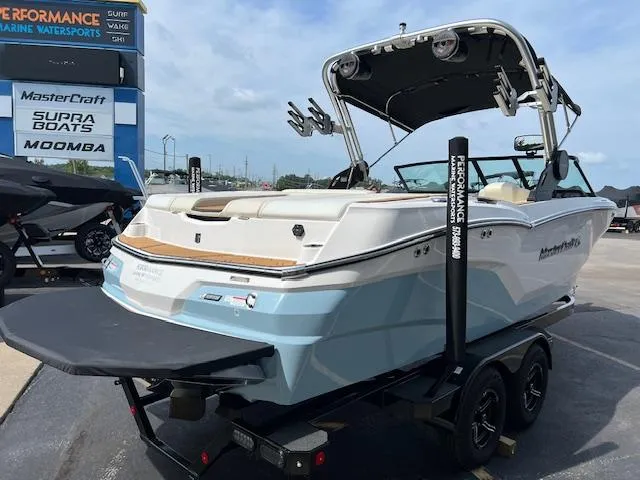 Slide: The Image of 2025 MasterCraft NXT23 boat on trailer at dealership, showcasing sleek design and modern features. - 6