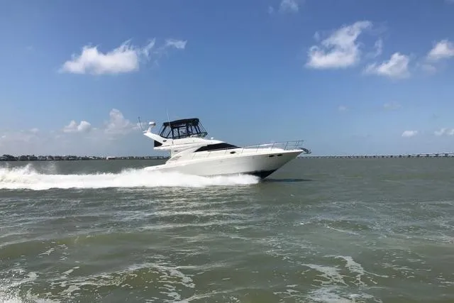 The Image of 2002 Sea Ray 400 Sedan Bridge cruising on open water under a clear blue sky. - 0