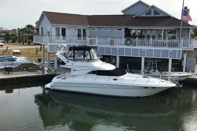 Slide: The Image of 2002 Sea Ray 400 Sedan Bridge yacht docked by a waterfront house. - 1