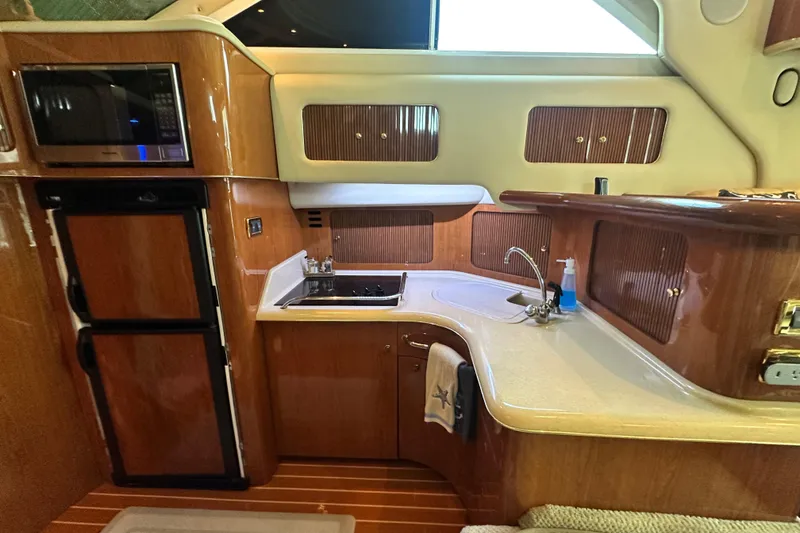 Slide: The Image of Luxurious kitchen area in a 2001 Sea Ray 400 Sedan Bridge yacht, featuring wood cabinetry and modern appliances. - 27