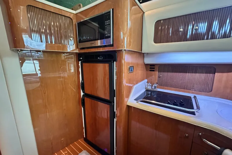 Slide: The Image of 2001 Sea Ray 400 Sedan Bridge kitchen with wood cabinetry, stove, and microwave. - 33