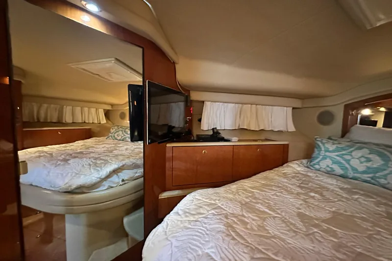 Slide: The Image of Interior of 2001 Sea Ray 400 Sedan Bridge, featuring cozy bedroom with TV and wood cabinetry. - 48