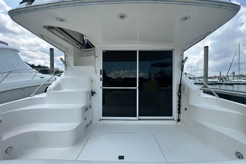Slide: The Image of 2001 Sea Ray 400 Sedan Bridge yacht stern view at marina, featuring spacious deck and sliding doors. - 9