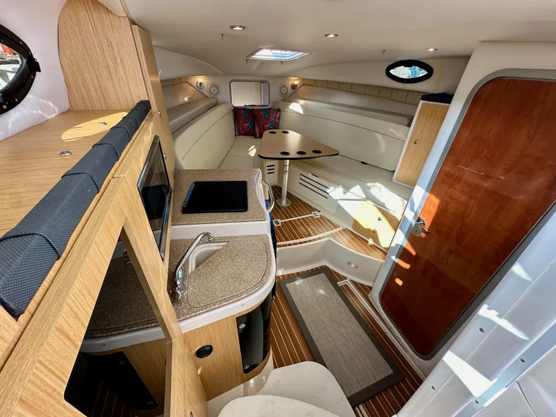 Slide: The Image of 2018 Wellcraft 290 Coastal cabin interior with kitchenette, seating, and wood accents. - 27