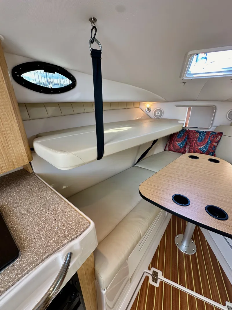 Slide: The Image of 2018 Wellcraft 290 Coastal cabin interior with seating, table, and porthole window. - 30