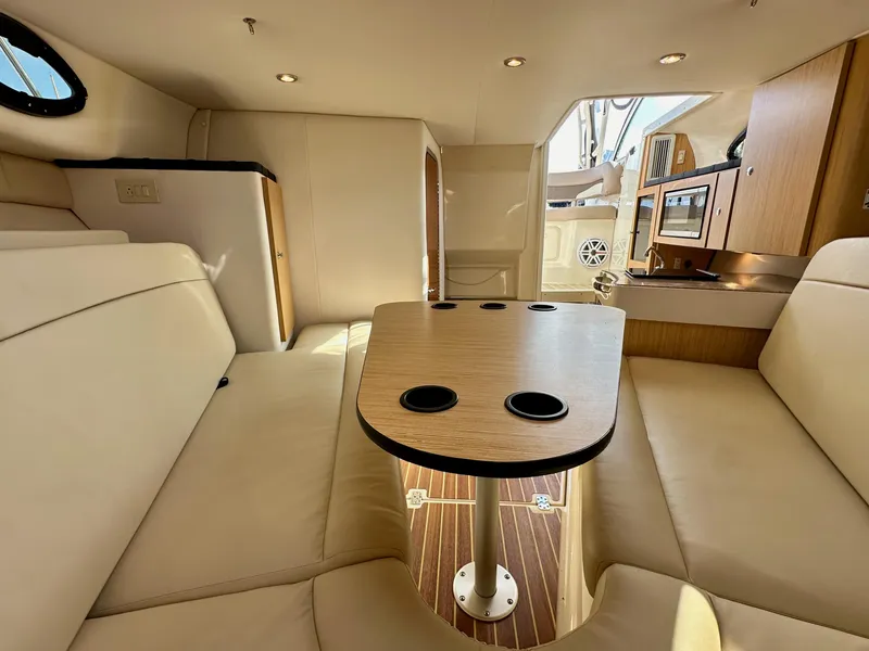 Slide: The Image of 2018 Wellcraft 290 Coastal interior with beige seating, wooden table, and kitchenette. - 33