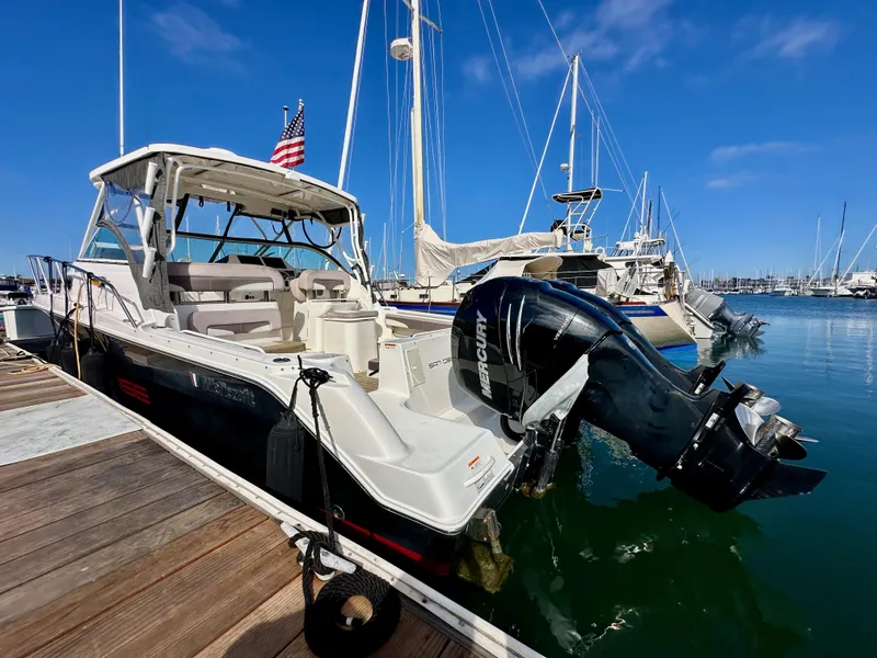 Slide: The Image of 2018 Wellcraft 290 Coastal boat docked, featuring Mercury outboard engine, clear blue sky. - 8