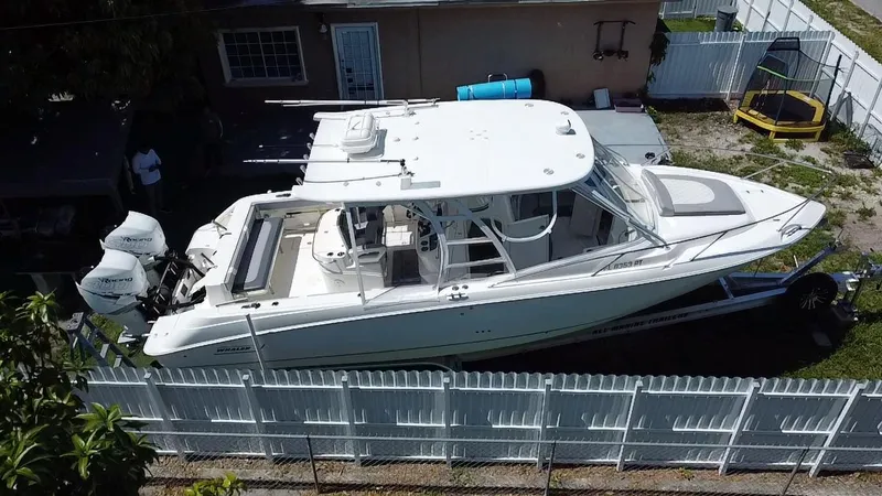 Slide: The Image of 2007 Boston Whaler 320 Outrage Cuddy Cabin boat on trailer, parked in a fenced yard. - 19