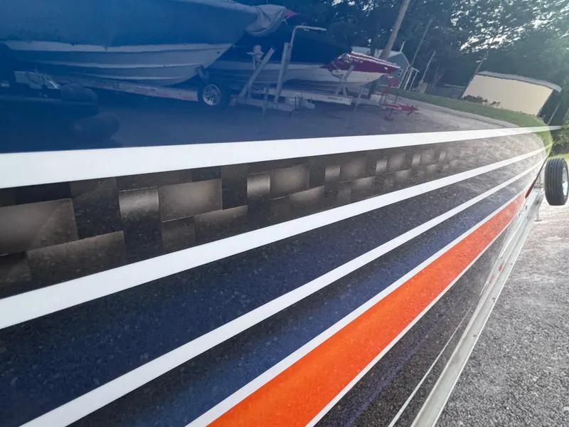 Slide: The Image of 2023 Fountain 38 SC boat with sleek, colorful side stripes in a marina setting. - 1