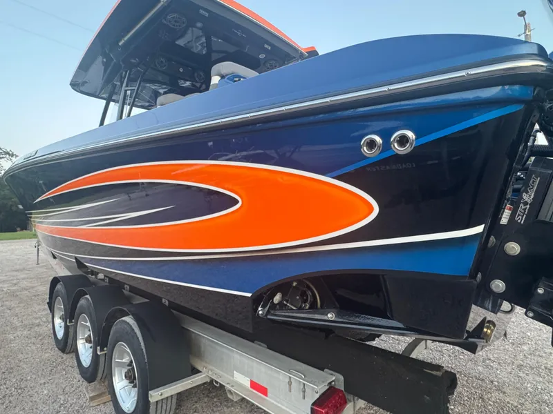 Slide: The Image of 2023 Fountain 38 SC boat with vibrant orange and blue design on a trailer. - 17