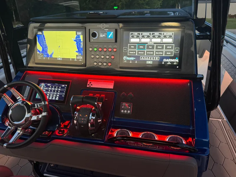 Slide: The Image of 2023 Fountain 38 SC boat dashboard with illuminated controls and Garmin navigation screens. - 43