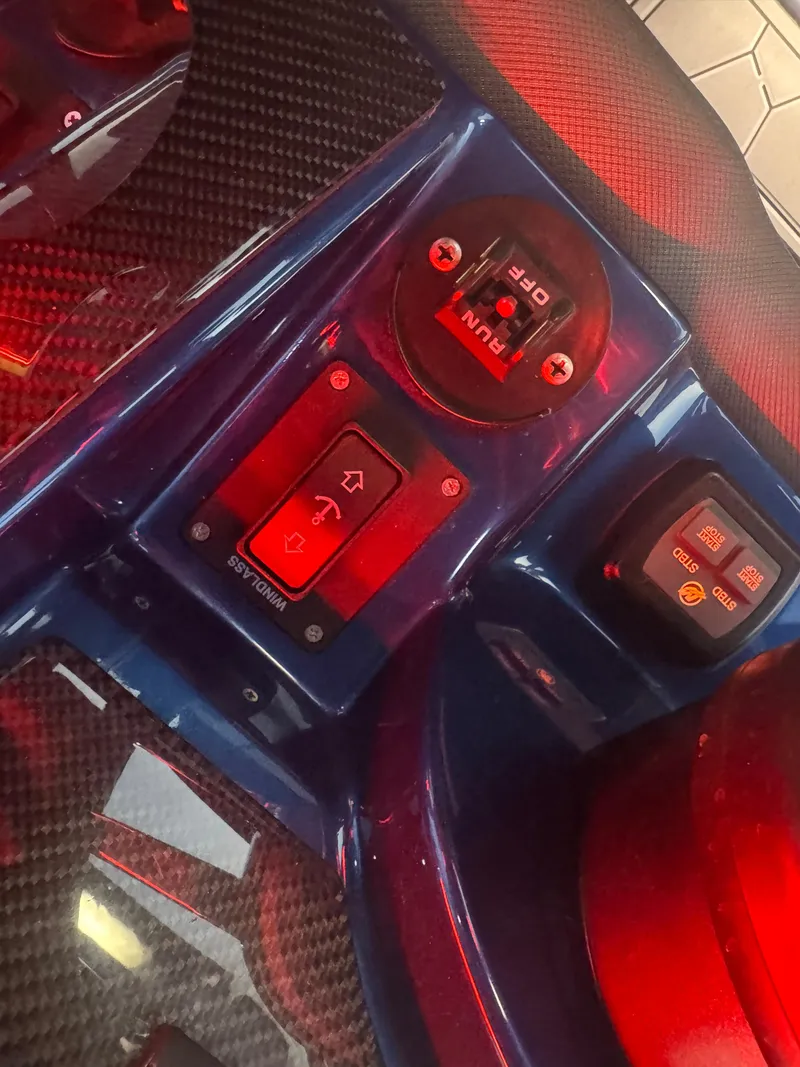 Slide: The Image of Control panel of 2023 Fountain 38 SC boat with illuminated switches and carbon fiber accents. - 49