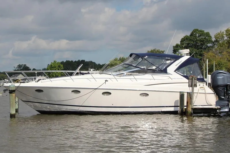 The Image of 2004 Regal Commodore 3860 yacht docked on a calm lake under cloudy skies. - 0