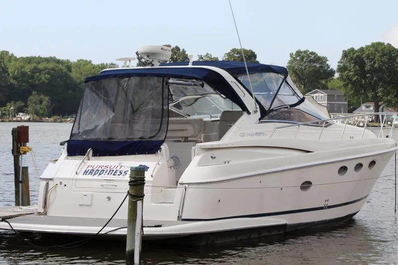 Slide: The Image of 2004 Regal Commodore 3860 yacht docked on a serene lake with lush greenery. - 2