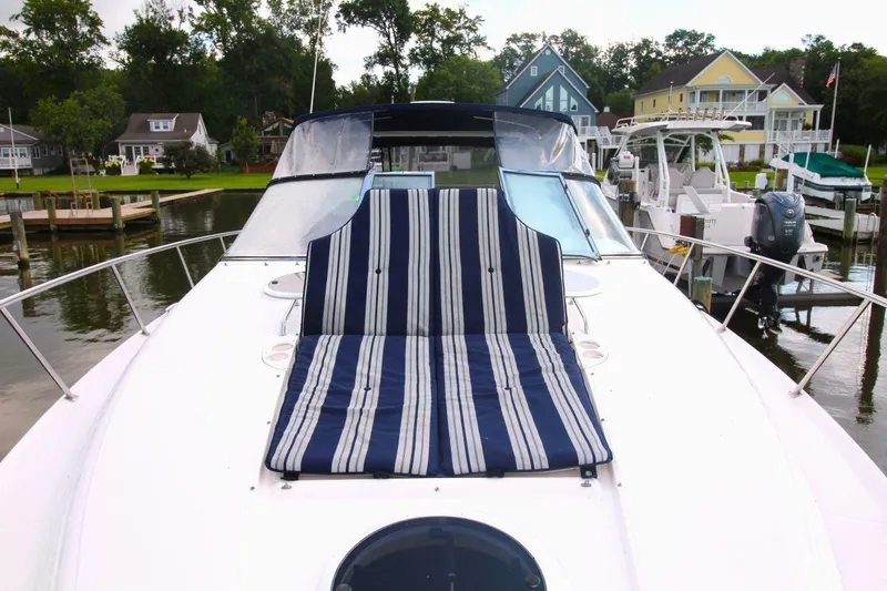 Slide: The Image of 2004 Regal Commodore 3860 yacht with striped deck seating, docked near waterfront homes. - 6