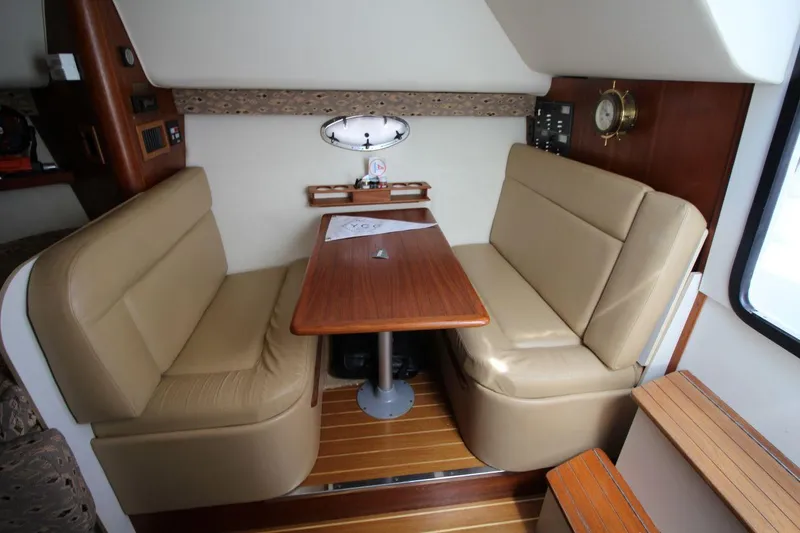 Slide: The Image of Interior of 2001 Tiara Yachts 2900 Open, featuring a cozy dining area with beige seating. - 17