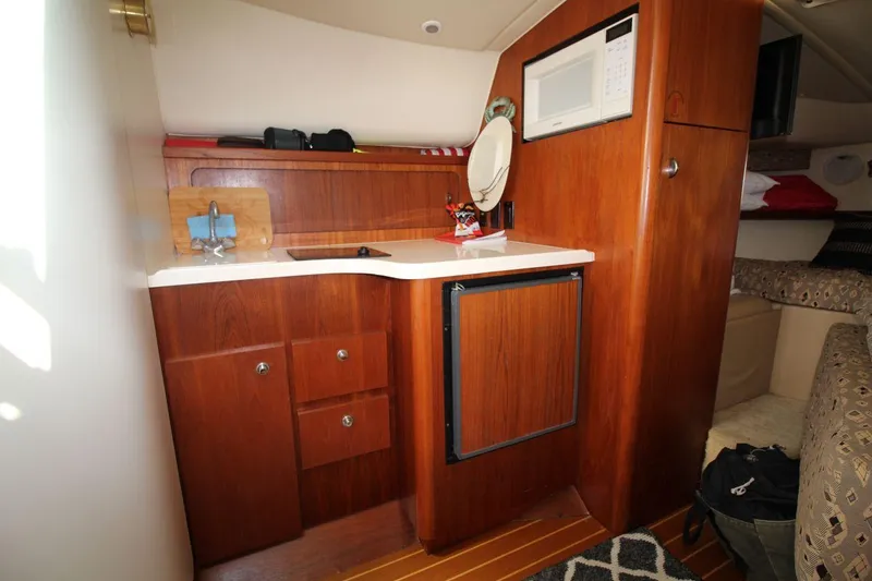 Slide: The Image of 2001 Tiara Yachts 2900 Open cabin interior with wood cabinetry and compact kitchen area. - 18