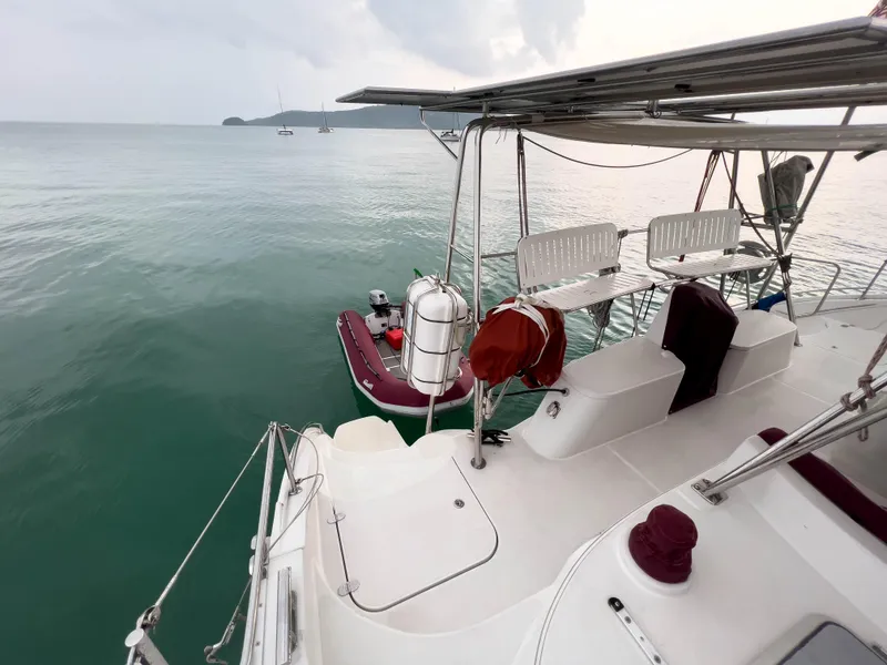 Slide: The Image of 2005 Antares PDQ 44 catamaran on calm sea with dinghy and seating area. - 14