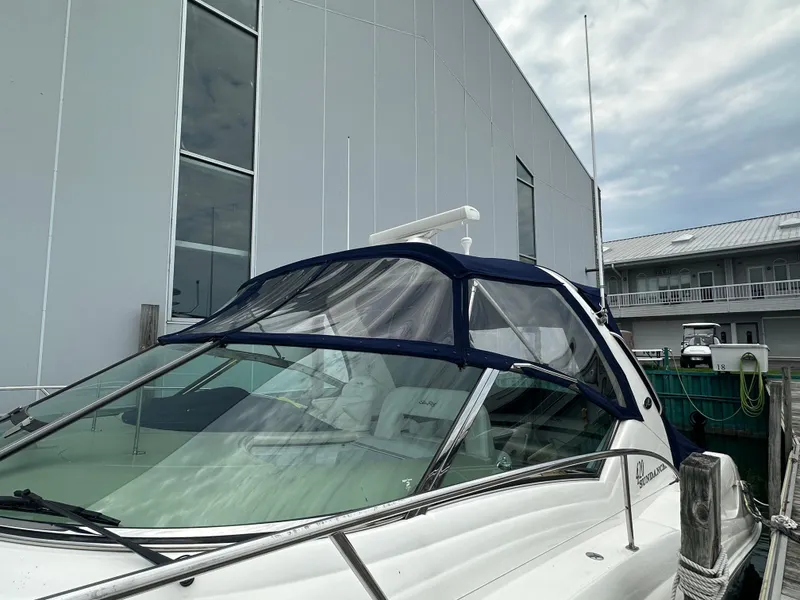 Slide: The Image of 2003 Sea Ray 420 Sundancer docked beside a modern building under a cloudy sky. - 5