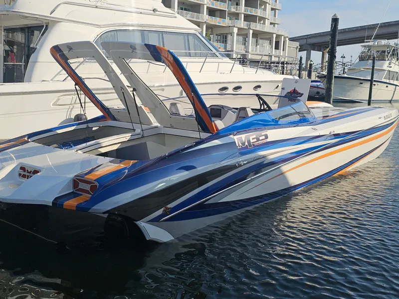 Slide: The Image of 2010 Daves Custom Boats M35 with vibrant stripes, parked on gravel near a truck. - 14
