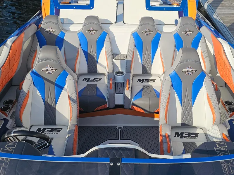 Slide: The Image of 2010 Daves Custom Boats M35 with vibrant blue and orange accents, displayed outdoors. - 2