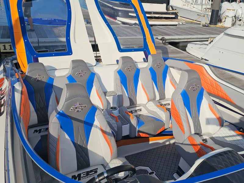 Slide: The Image of 2010 Daves Custom Boats M35 interior with vibrant orange and blue accents, docked by water. - 28
