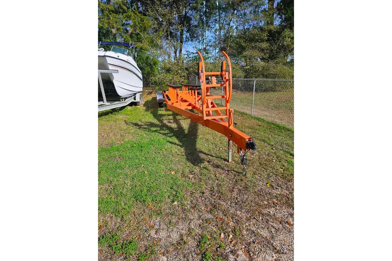 Slide: The Image of Orange boat trailer beside a 2010 Daves Custom Boats M35, parked on grass. - 53