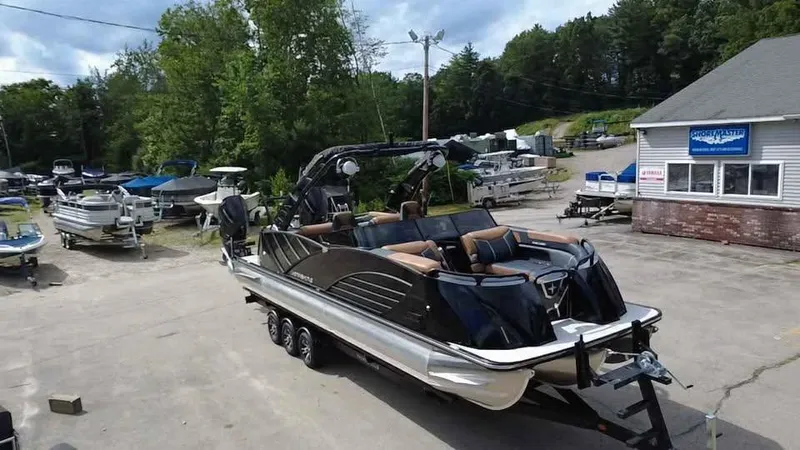 Slide: The Image of 2025 Berkshire 25 Sport RFX9-DC pontoon boat on trailer in marina parking lot. - 2