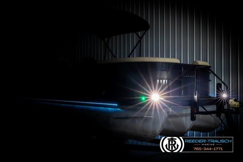 Slide: The Image of 2023 Lowe 210 SSTL pontoon boat with illuminated lights in a dimly lit setting. - 4