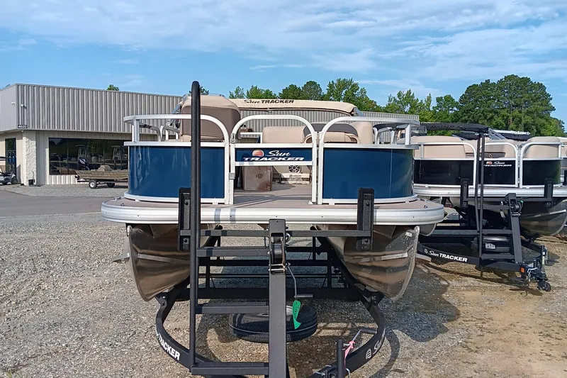 Slide: The Image of 2025 Sun Tracker Bass Buggy 16 XL Select pontoon boat on trailer, dealership background. - 5