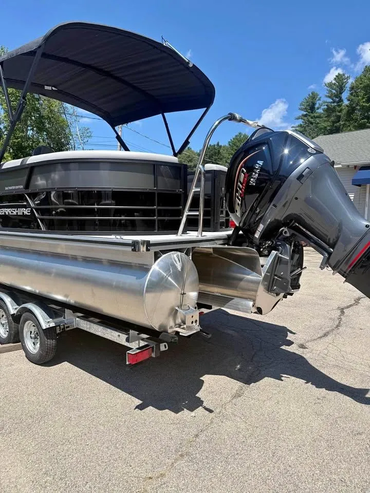 Slide: The Image of 2025 Berkshire 22RFX CTS pontoon boat on trailer with outboard motor, under blue sky. - 2