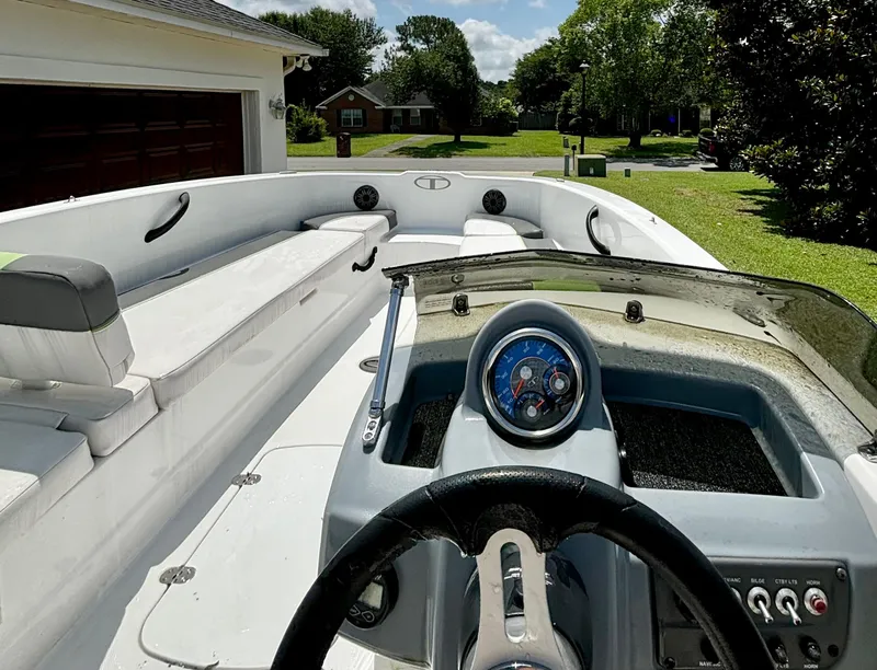Slide: The Image of 2022 Tahoe T18 boat interior with steering wheel and seating, parked in a residential driveway. - 3
