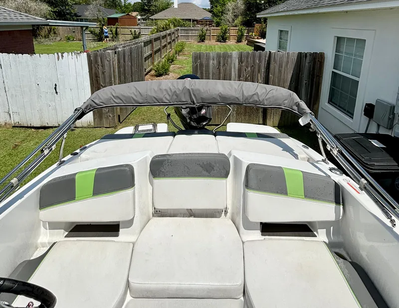Slide: The Image of 2022 Tahoe T18 boat interior with gray and green seating, parked in a residential backyard. - 5