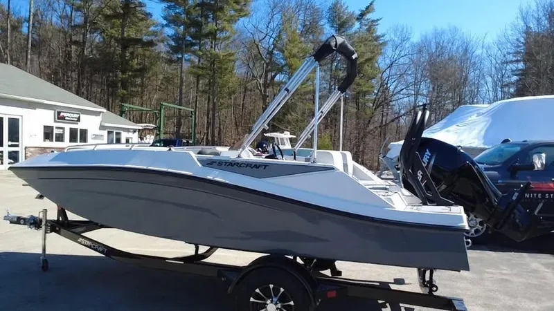 Slide: The Image of 2025 Starcraft SV 16 OB boat on trailer, parked outdoors near trees and buildings. - 6