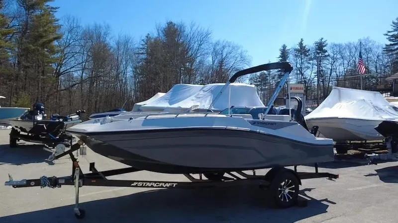Slide: The Image of 2025 Starcraft SV 16 OB boat on trailer, parked outdoors with trees in the background. - 8