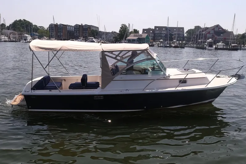 The Image of 2005 Hunt Yachts Surfhunter 25 boat on calm water, with canopy and marina background. - 0