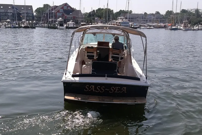 Slide: The Image of 2005 Hunt Yachts Surfhunter 25 named "Sass-Sea" on calm waters near a marina. - 5