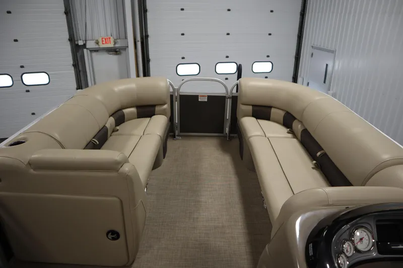 Slide: The Image of 2023 Tracker 20 DLX PARTY BARGE interior with beige seating in a garage setting. - 11